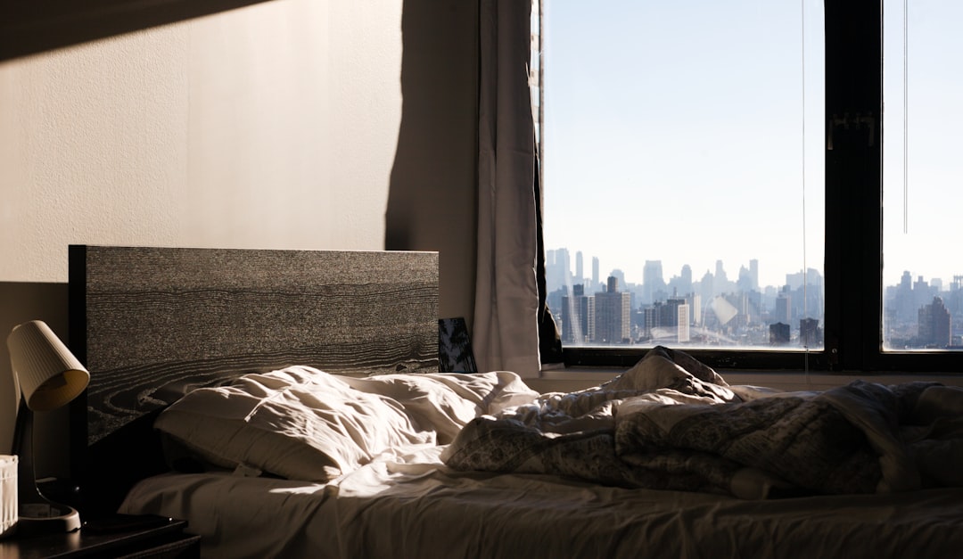 an-unmade-bed-with-a-view-of-the-city-kuuvq4nbchk